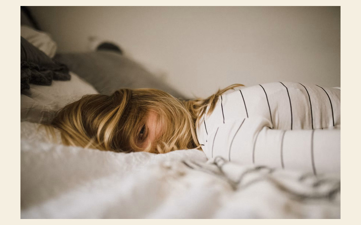 Tired parent lying awake on a bed, representing parent sleep loss.